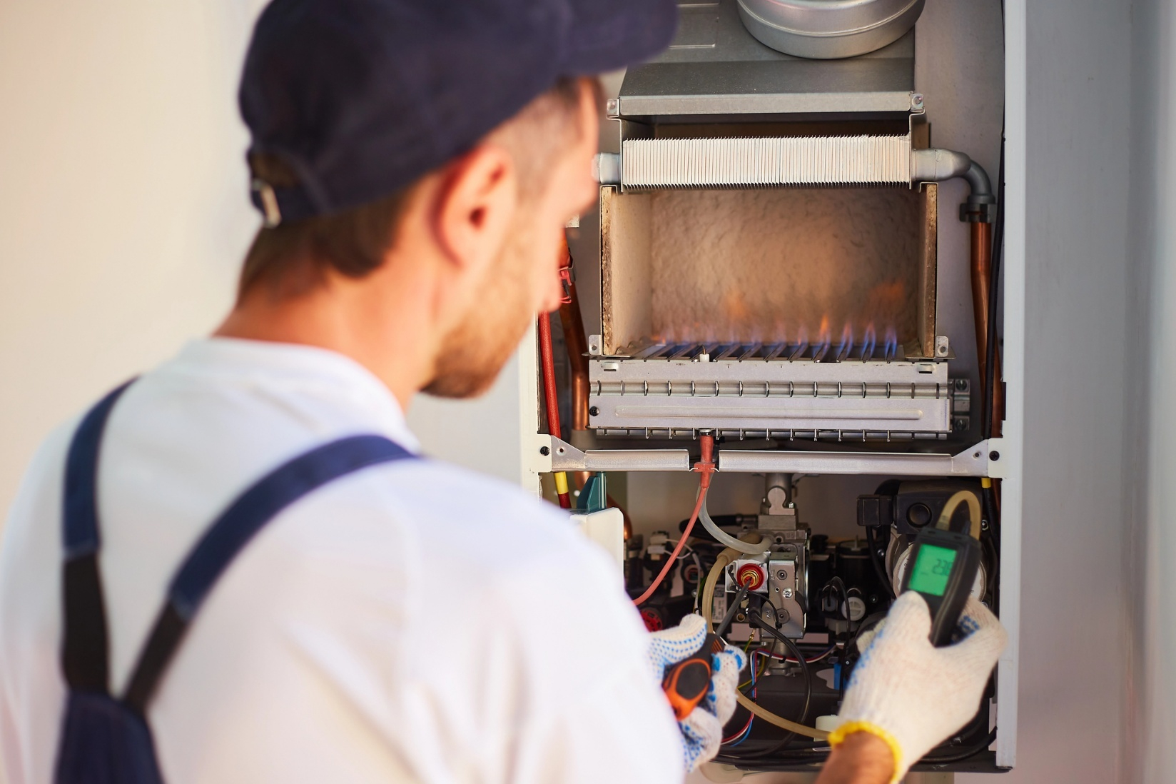 An HVAC technician adjusts the combustion of the gas in the furnace equipment