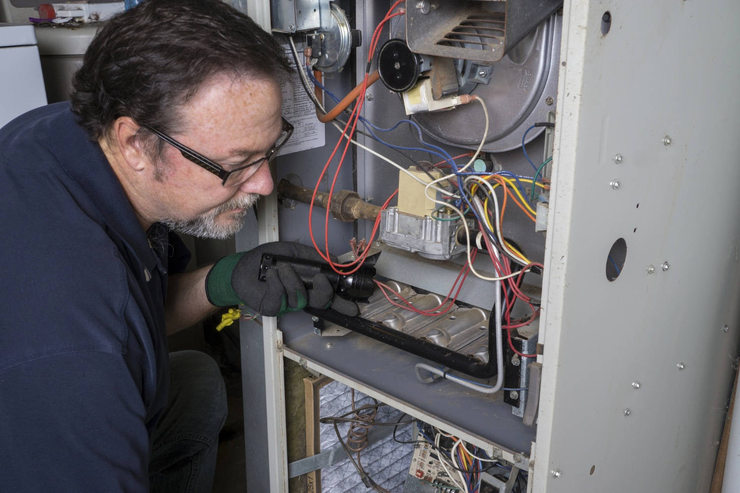 A technician is looking over a gas furnace